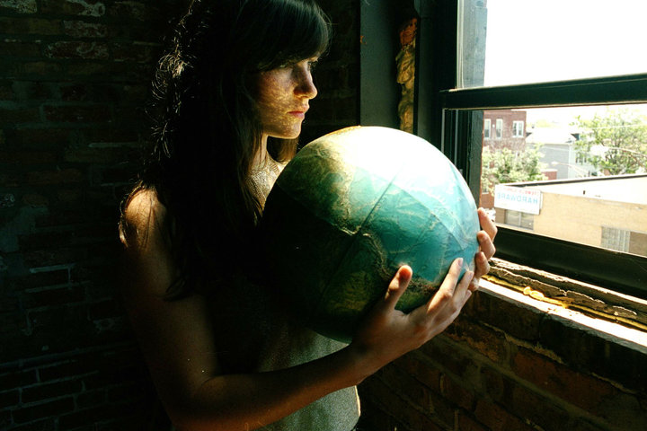 Writer and performer, Annika Franklin, holding a globe by a window.